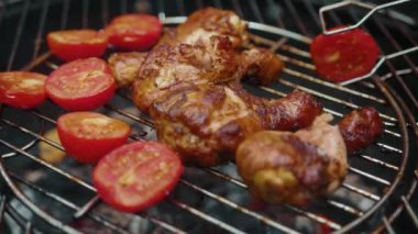 Barbekü. Piknik. Birisi ızgarada yanan kömürle sulu tavuk eti ve domates pişiriyor. Sıcak alev. Hazırlık. Yakın plan..