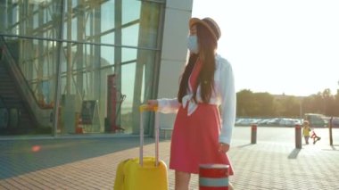 Asyalı güzel bayan gezgin, koruyucu maske takan genç iş kadını güneşli bir sabah güneşli bir havada havaalanına yürüyor. Coronavirus. Karantinaya alın. Sağlık Hizmetleri.