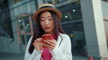 Harika genç Çinli kadın havaalanı terminali yakınlarında akıllı telefon haritası kullanarak güzel şehri keşfediyor. İnsanlar ve teknoloji. Açık havada..