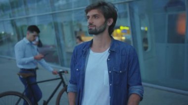 Modern binanın yakınında günlük kıyafetlerle gezen beyaz tenli yakışıklı bir adam. Cazibeli, kaygısız, sakallı genç adam havaalanı yakınlarında moda gezgini. Geldik. Turizm. İnsanlar.