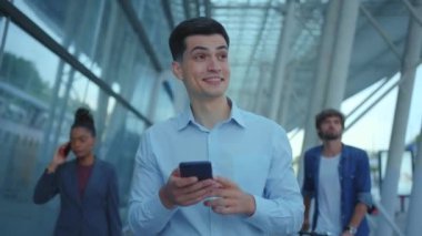 Yakışıklı beyaz adam akıllı telefon uygulamasına bakıyor gülümsüyor şehir turundan keyif alıyor havaalanı yakınlarında yeni bir ülkeyi keşfediyor. İş için. Kariyer insanları.