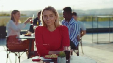 Yazlık kafede dinlenen genç ve çekici bir kadın kameraya bak. Yüz taraması, sokak arkadaşlığı modelleri, açık hava ağır çekim.