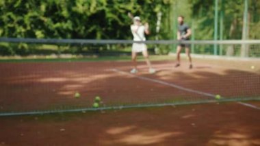 Genç bir kadın ve erkek tenis oynuyorlar. Atletik güçlü atletik oyun antrenmanı. Boş zamanlardaki spor tenis topunu yavaş çekimde oynuyorlar.