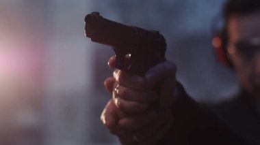 Kapalı ellerde bir adam bir kadına tabancayla nasıl ateş edileceğini öğretir. Hızlı ateş eder. Kız polis atış talimi yapar.