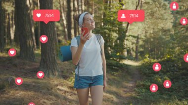 Sırt çantalı portre kadın akıllı telefon yürüyüşü yapıyor. Güneşli bir yaz gününde sonbahar ormanında çevrenize bakın. Vlogger kullanıcı arayüzü ile canlandırıcı - beğeni, takipçi, sosyal medya yorumları