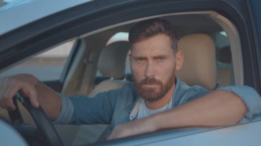 Şen günbatımında gülümseyen, modern lüks bir arabanın içinde şehir merkezinde oturan neşeli genç adamın inanılmaz portresi..