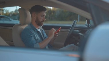 Cep telefonu kullanan yakışıklı bir iş adamının profili modern bir arabada oturmuş şehir merkezinde online haritası olan bir turizm rotası planlıyormuş..