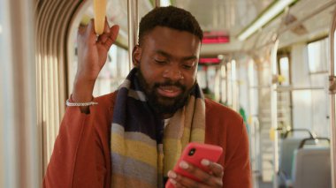 Portre Afro-Amerikalı adam kameraya bak tramvay trafiğinde akıllı telefon standı kullan yakışıklı yolcular stil nakliyat internet mesajcı çocuk yavaş çekim kullanarak