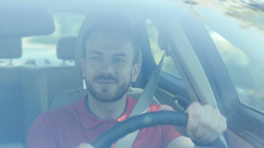 Mutlu, genç, gülümseyen bir adam araba kullanıyor. Gün batımı yolculuğunda. Mutlu, macera dolu bir araba.