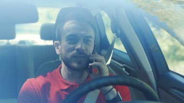 Gülümseyen genç, yakışıklı, mutlu adam arabada telefon kullanıyor. Kamera sürücüsü, mobil mobil sürücü, el bilgisayarı, akıllı telefon, iş dünyası iletişim işadamı telefon.