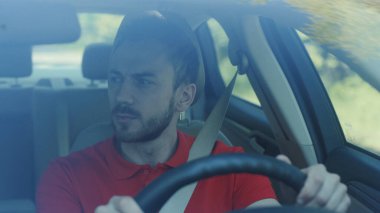 Ciddi bir genç adam araba kullanıyor. Gün batımı yolculuğunda. Mutlu bir macera arabası. Kısa saçlı, serbest zaman yolculuğu.