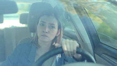 Ciddi genç kadın sürücü araba kullanırken gün batımı iletişimi sırasında telefon kullanıyor. Yetişkin cep telefonu, tehlikeli otomobil bağlantı yolu. Akıllı telefondan ağır çekimde mesaj atıyor.