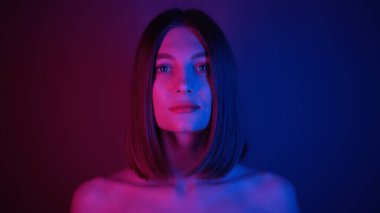 Mavi gözlü muhteşem genç bayanın yakın çekimi. Harika bir kız kameraya bakıyor. Güzel özellikler. Neon ışıkları. Bob saç stili. Şık, aydınlık