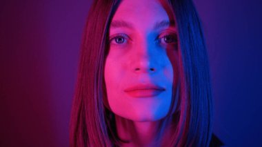 Mavi gözlü muhteşem genç bayanın yakın çekimi. Harika bir kız kameraya bakıyor. Güzel özellikler. Neon ışıkları. Bob saç stili. Şık, aydınlık