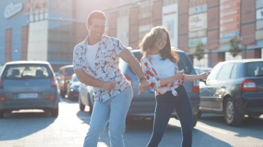 NEW YORK - 10 Haziran 2018: Latin salsa sosuyla dans eden mutlu çift otoparkta birlikte hareket ediyor. Melez ırk çekici kız ve erkek gün ışığında açık havada gösteri yapıyorlar..