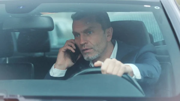 Close up view of handsome man in luxurious car impatiently beeping car horn while not moving in the traffic jam, then angrily talking on the phone and actively waving his arms. Stress, trouble