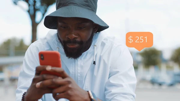 App Icon with Online transaction. Financial Transactions in the Smartphone. Receive a Message About Increase Money. Happy Stylish Young Bearded African American Man Walks Uses Phone Smiles City.
