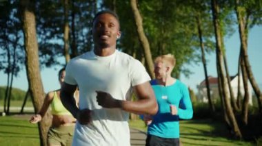 Gelecekteki maraton için birlikte koşan üç harika atletik insan grubu halka açık parkta fiziksel yoğun egzersizler yapıyorlar. Koşu takımı. Üçlü çalışma.