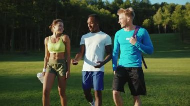 Güzel üç genç profesyonel sporcu dışarıda yoğun bir kardiyo antrenmanı yaptıktan sonra parkta komik sohbetler yapıyorlar. Spor üçlüsü. Rüya takım..