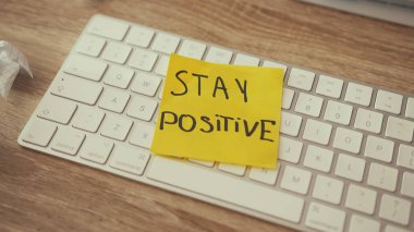 Yaratıcılık krizi ve fikir eksikliği. Buruşuk kağıtlı dağınık sanatçı iş yeri masaüstü. Adam klavyeye olumlu bir etiket yapıştırıyor. Motivasyon kavramı.