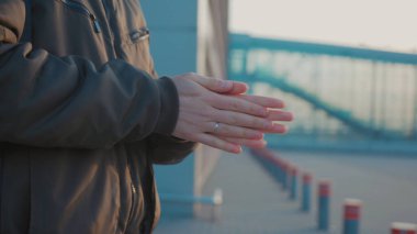 Güneş ışığında insan, antiseptik dezenfektan spreyi sıkar ve havaalanı yakınlarındaki COVID-19 koronavirüs enfeksiyonunu önler.