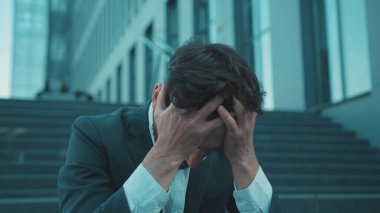 Kapat yüzünü, üzgün genç adam merdivenlerde oturuyor kafası kişisel eşyalarla dolu, Coronavirus krizi yüzünden işten atıldı iş dünyası ağır çekim ekonomisi.