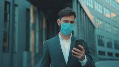 İş adamı maske takıyor. Telefon kullanıyor. Virüs koruma ilacı pandemik karantina koronavirüs krizi.