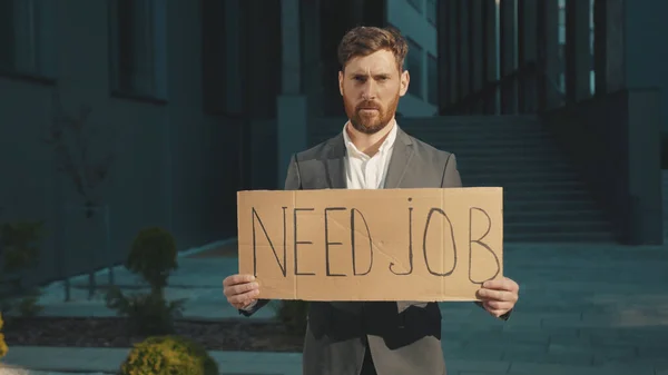 Portrait young businessman holding poster cardboard with Need Job jobless message sign coronavirus crisis text job showing professional finance economy slow motion
