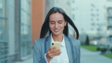 Çekici gülümseyen iş kadını telefon yürüyüşü yapıyor. İş merkezi takımının yakınına bak. Başarılı teknoloji çekici, yavaş çekim.