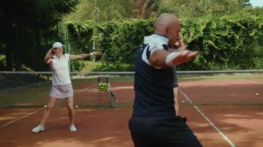 Güneşli bir günde, oyuncular tenis maçından önce antrenörle ısınırlar. Antrenman antrenmanı, egzersiz, spor salonu, spor salonu, spor salonu, yaz, yavaş çekim.