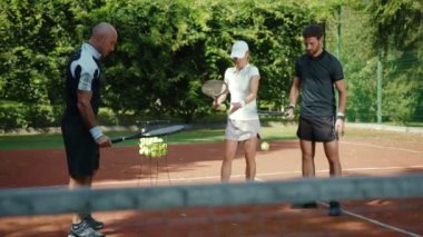 Yavaş çekim koçu bir kortta tenis oynayan erkek ve kadına oyun öğretiyor. Spor oyuncuları etkinliği maç maç spor giyim spor antrenmanı cevap yaz antrenmanı eğitmenini kapatın.