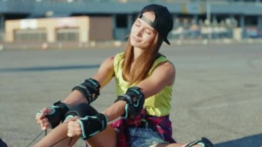 NEW YORK - 5 Nisan 2020: Güzel kız yerde oturuyor ve patenleri gülümsüyor yaz aylarında mutlu bir cadde hisset bacaklar ağır çekimde patinaj yapıyor