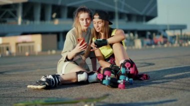 Paten kayarak yerde oturan genç kadınları yaz aylarında gülümseyen mutlu caddeleri hisset.