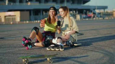 Paten kayan ve konuşan genç kadınları kapat. Telefonu kullan. Gülümse ve yaz aylarında mutlu bir sokak hisset.