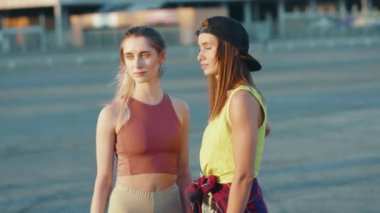 İki hoş adamın portresi, kameraya bak, dışarıda kayıyor, spor sokak bacakları kaykay yapıyor, arkadaşları ağır çekimde patenle kayıyorlar.