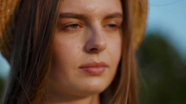 Ciddi genç kadın yüzü şapkasıyla açık gözlerle güneşli yaz günü açık hava seyahati kız sağlıklı açık hava özgürlüğü çekici gün batımı rahatla ağır çekim gülümseyen saçlar