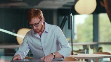 Genç yakışıklı yönetici kafkasyalı adam halka açık restoranda oturuyor bilgisayarını açıyor ve içeride video iş görüşmesi yapıyor. Teknoloji.