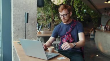 Akıllı Zencefilli Ofis Yöneticisi Yönetici Yöneticisi laptop bilgisayarında çalışıyor kahve içiyor modern restoranda öğle yemeği yiyor. Ortak çalışma alanı. İşadamı.