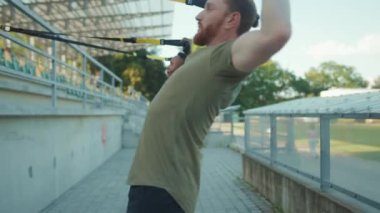 NEW YORK - 5 Eylül 2020: Ağır çekimde iki genç adam trx fitness halatıyla dışarıda vücut egzersizleri yapıyor stadyum kaslı Afrikalı Amerikan spor giyim spor giyim spor giyim sporu antrenmanları yapıyor.