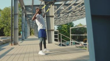 NEW YORK - 5 Eylül 2020: Trx fitness halatıyla çalışan genç, Afro-Amerikalı adam stadyum kaslı spor kıyafetleri spor antrenmanlarında vücut egzersizleri yapıyor.