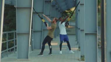 NEW YORK - 5 Eylül 2020: Trx fitness halatıyla çalışan iki adam stadyum kaslı Afrika kökenli Amerikan spor kıyafetleri spor kıyafetleri spor salonlarında vücut egzersizleri yapıyor.