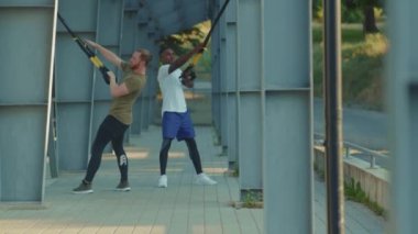 NEW YORK - 5 Eylül 2020: Trx fitness halatıyla çalışan genç yakışıklı erkekler stadyum kaslı Afrikalı Amerikan spor giyim sporları antrenmanlarında vücut egzersizleri yavaş