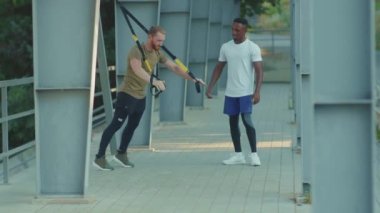 NEW YORK - 5 Eylül 2020: Trx fitness halatıyla çalışan iki genç adamı kapatın stadyumdaki Afrika kökenli Amerikan spor giyim sporları antrenmanlarında vücut egzersizleri yavaş