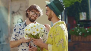 Genç iki eşcinsel erkek gün ışığında çiçeklerle fotoğraf çekiyor mutlu homoseksüel çiftler LGBT ilişkilerinde gülümsüyor açık havada erkek arkadaş cezbedici yavaş çekim.