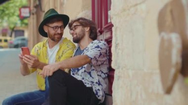 Mutlu eşcinsel çift dışarıda takılıyor, telefonda sarılıyor, ilişki kuruyor, romantik bir ilişki kuruyor, yaz tatilinde güneşli bir aşk yaşıyor, şakacı mesajlar atıyor, sohbet ediyor, homoseksüel yavaş çekim.