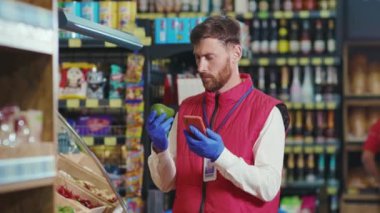 Genç satıcı süpermarkette avakado kullanır. Karantina zamanı sebze işinde avakado kullanır. Güzel, taze ürünler, perakende satış yapan gıdalar.