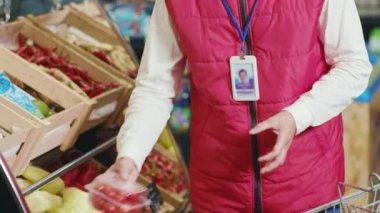Ciddi genç satıcı sebzeleri süpermarketin raflarına koyar sebzeleri kontrol eder güzel, taze, perakende satış mağazaları yavaş çekim yapar.