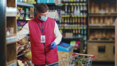 Maskeli genç satıcı süpermarket sebze işinde kontrol ediliyor. Güzel, taze, perakende satış mağazası yavaş çekim.