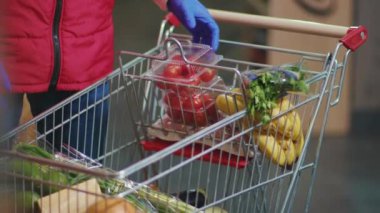 Sebzeler ve meyveler süpermarketin el arabasında. Adam sebzeleri süpermarketin ağır çekimde rafına koyuyor.