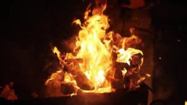 Karanlık bir gecede kamp ateşi odunu yanmış kömür alevi görüntülerini yakar dışarıda piknik arka planında ateş kömürü portakalı yavaş çekimde kapanıyor.